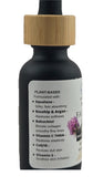 Black bottle with wooden cap and label detailing plant-based ingredients on a white background